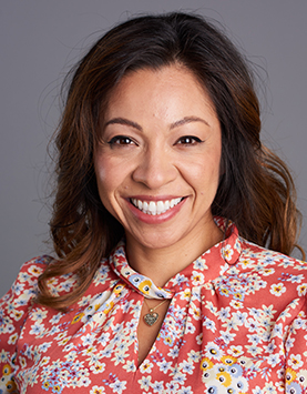 Latinx woman with shoulder length wavy hair wearing a floral blouse