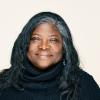 African American woman, gray hair wearing a black knit poncho