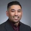 Asian American male wearing a burgundy dress shirt and black suit jacket.