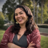 Headshot of mixed race (Asian/White) smiling woman in her late 40's, dark hair, light-colored skin, and dark features.