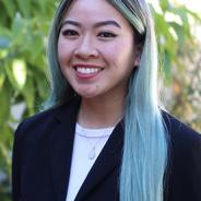 Asian woman smiling with black, blond, and blue hair wearing a blazer and a white shirt.