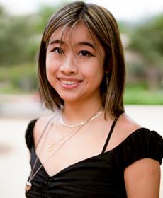 Asian woman with blonde highlights in her hair wearing a black top.